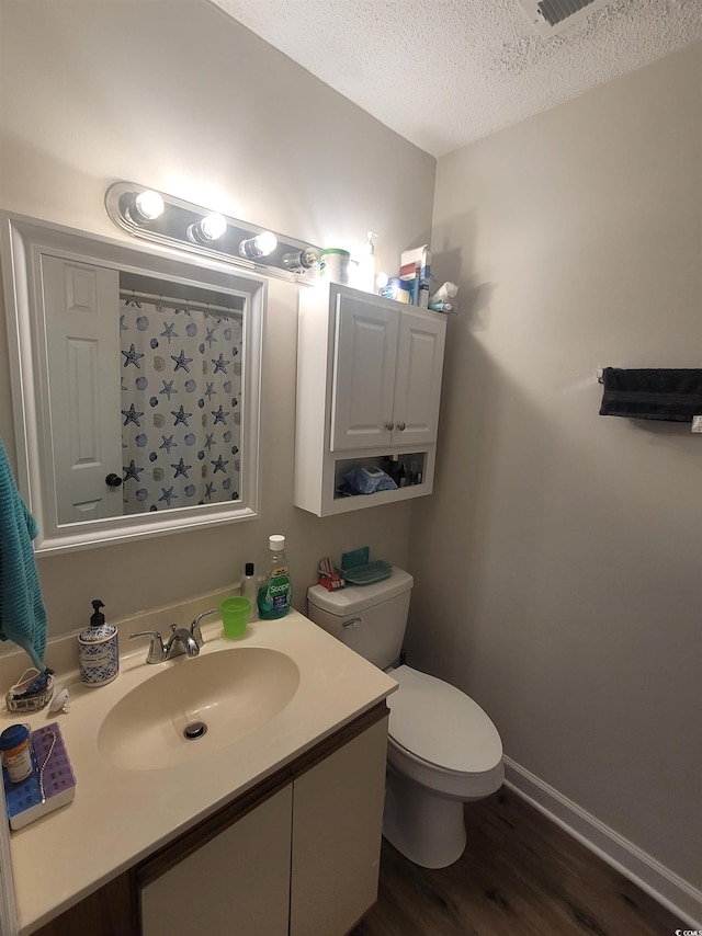 bathroom featuring a textured ceiling, wood-type flooring, vanity, and toilet