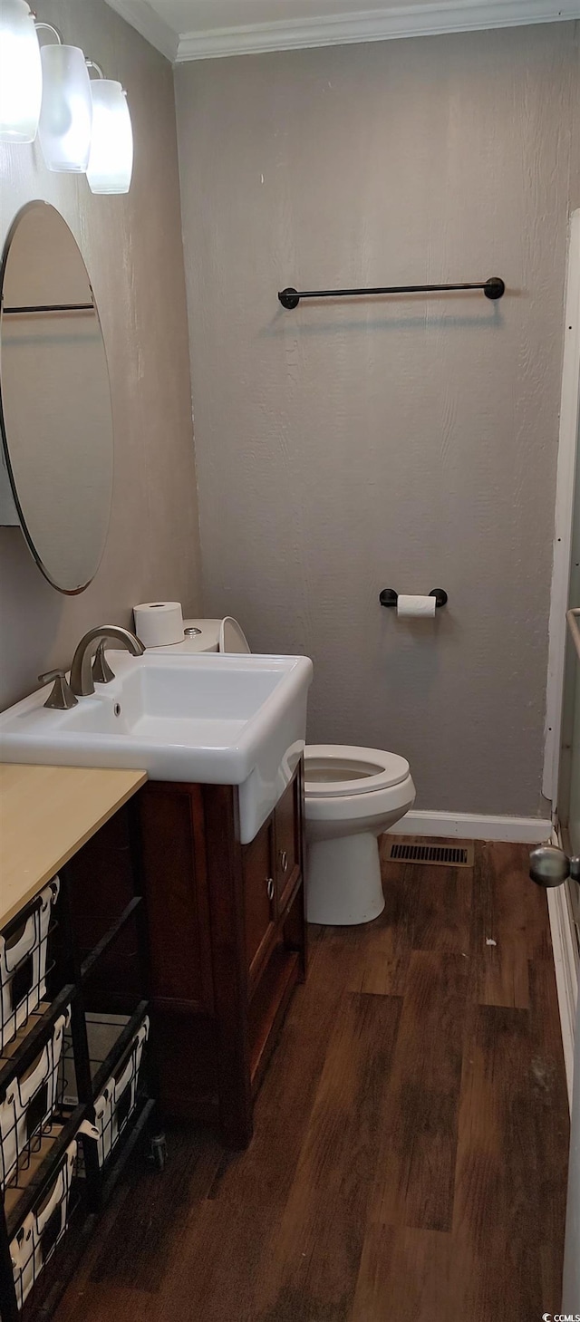 bathroom featuring toilet, ornamental molding, wood-type flooring, and vanity