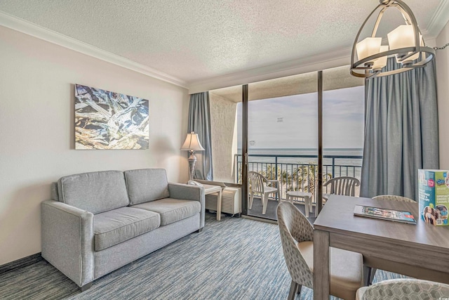 living room featuring ornamental molding, a notable chandelier, a textured ceiling, and a water view