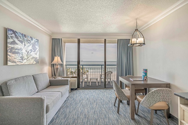 living room featuring an inviting chandelier, a water view, a textured ceiling, and crown molding