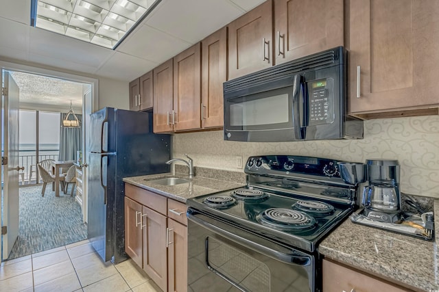 kitchen featuring light stone counters, black appliances, sink, and light colored carpet