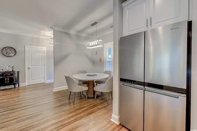 dining room with light hardwood / wood-style flooring and crown molding