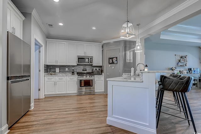 kitchen featuring stainless steel appliances, tasteful backsplash, hanging light fixtures, ornamental molding, and white cabinets