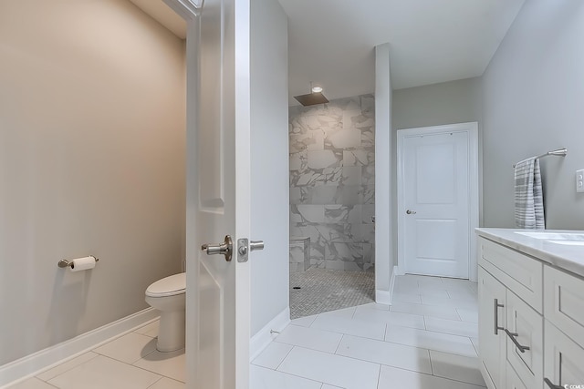 bathroom with tile patterned floors, vanity, a tile shower, and toilet