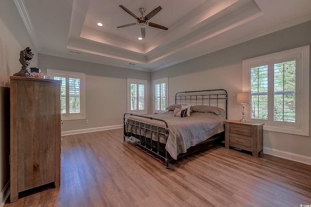 bedroom featuring ceiling fan, ornamental molding, hardwood / wood-style floors, and a tray ceiling