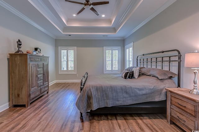 bedroom featuring ceiling fan, ornamental molding, a raised ceiling, and multiple windows