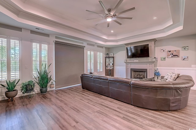 living room with ceiling fan, wood-type flooring, crown molding, and a tray ceiling