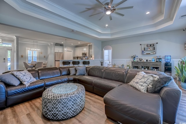 living room with ceiling fan, ornamental molding, and a raised ceiling