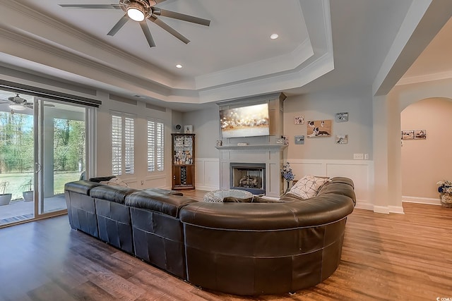 living room with ceiling fan, hardwood / wood-style floors, a tray ceiling, and ornamental molding