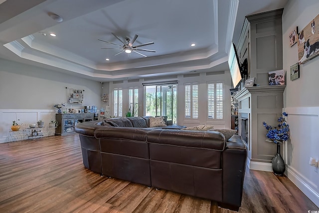 living room featuring dark wood-type flooring, a tray ceiling, and ornamental molding