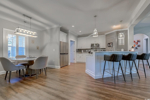 kitchen with white cabinetry, appliances with stainless steel finishes, kitchen peninsula, and tasteful backsplash