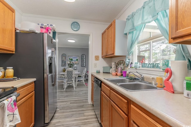 kitchen featuring light wood-type flooring, sink, appliances with stainless steel finishes, and ornamental molding