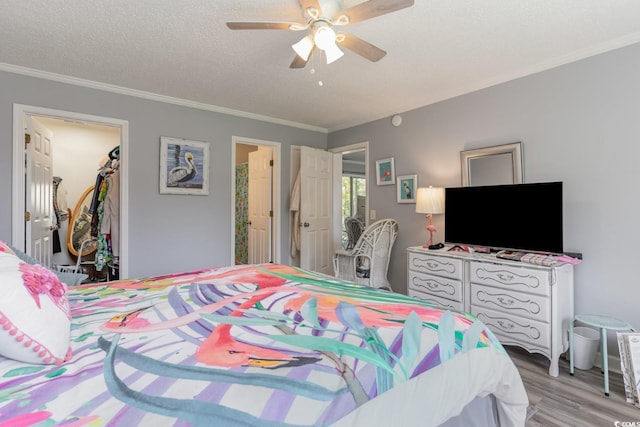 bedroom featuring ceiling fan, light hardwood / wood-style flooring, a textured ceiling, a closet, and ornamental molding