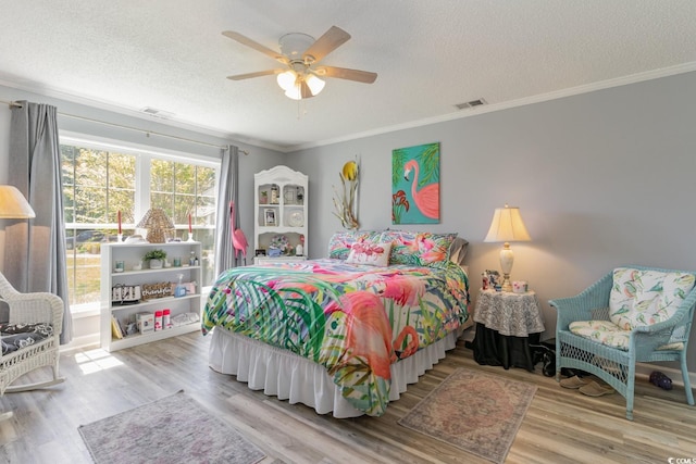 bedroom with a textured ceiling, ceiling fan, light wood-type flooring, and crown molding