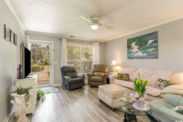 living room featuring a textured ceiling, light wood-type flooring, ceiling fan, and crown molding