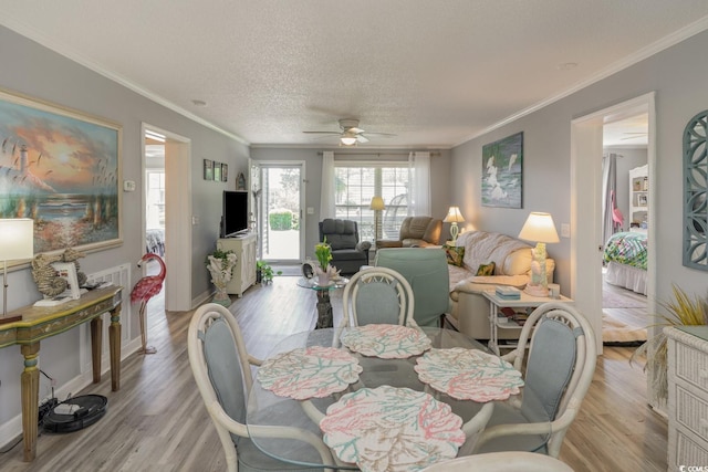 dining room featuring ceiling fan, ornamental molding, a textured ceiling, and light hardwood / wood-style flooring