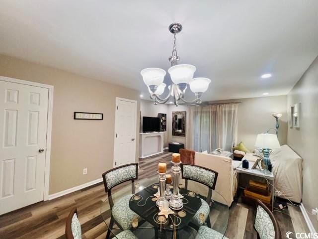 dining space featuring dark wood-type flooring and an inviting chandelier