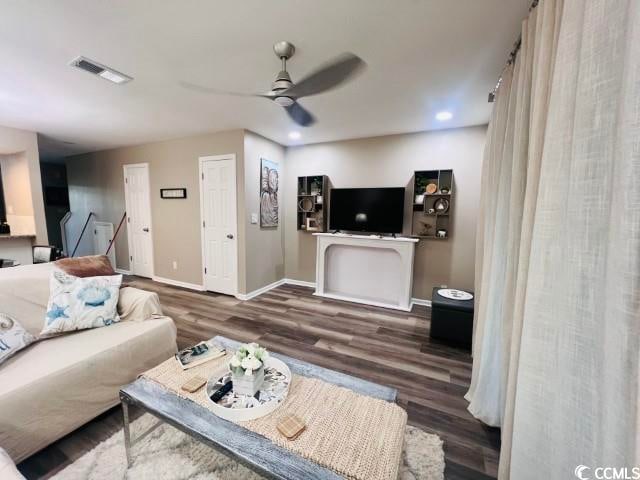 living room with ceiling fan and dark wood-type flooring