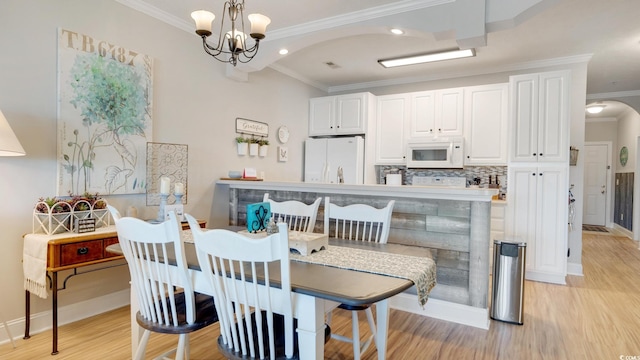 dining area featuring light hardwood / wood-style flooring, an inviting chandelier, and ornamental molding