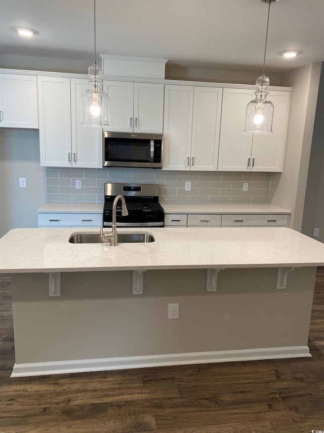 kitchen with appliances with stainless steel finishes, a center island with sink, and hanging light fixtures