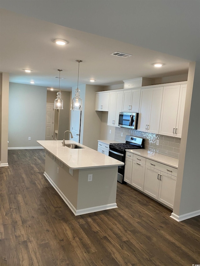 kitchen featuring a kitchen island with sink, stainless steel appliances, dark wood-type flooring, and white cabinets