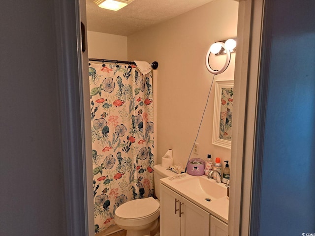 bathroom with vanity, toilet, and a textured ceiling