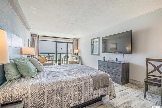 bedroom featuring a textured ceiling, light hardwood / wood-style floors, and a water view