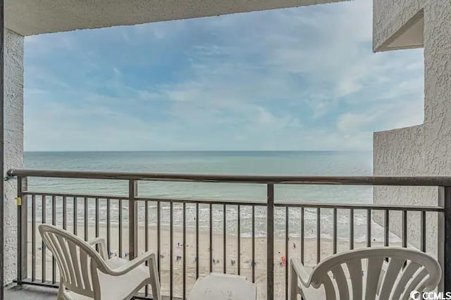 balcony with a water view and a view of the beach