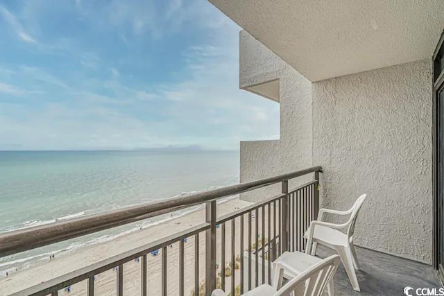 balcony featuring a view of the beach and a water view