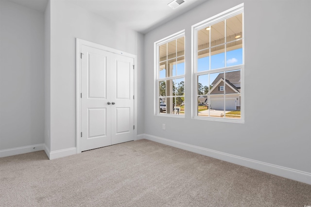 unfurnished bedroom featuring a closet and light colored carpet