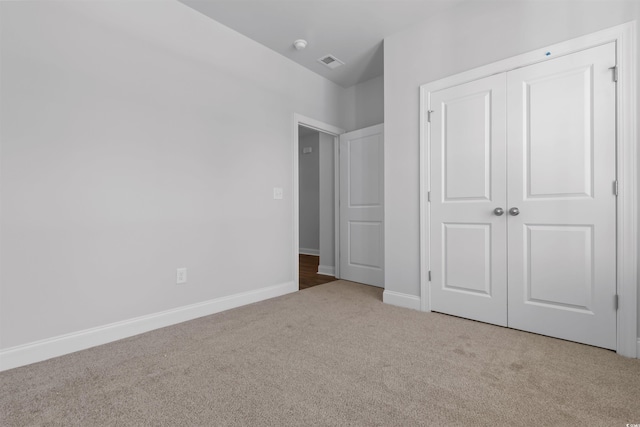 unfurnished bedroom with a closet and light colored carpet