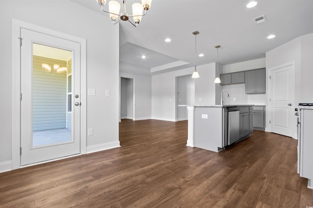 kitchen featuring gray cabinets, a center island with sink, hanging light fixtures, and dark wood-type flooring