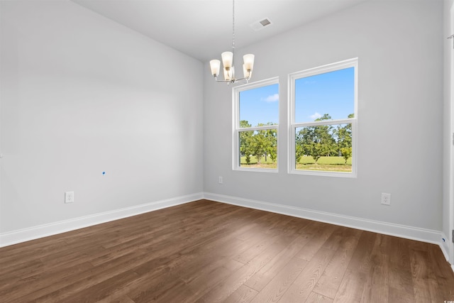 spare room with a chandelier and dark hardwood / wood-style floors