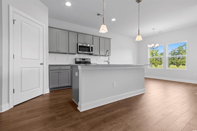 kitchen featuring pendant lighting, a kitchen island with sink, gray cabinets, appliances with stainless steel finishes, and dark hardwood / wood-style flooring