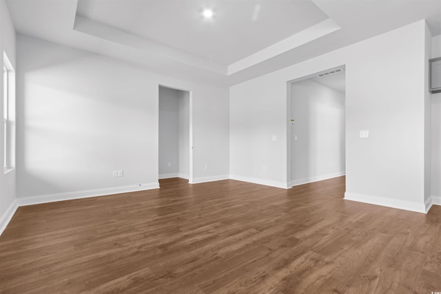 spare room featuring dark hardwood / wood-style floors and a raised ceiling