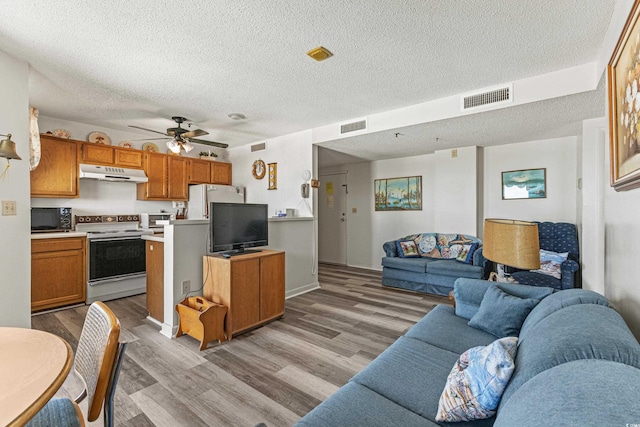 kitchen with white range with electric stovetop, refrigerator, light hardwood / wood-style floors, ceiling fan, and a textured ceiling