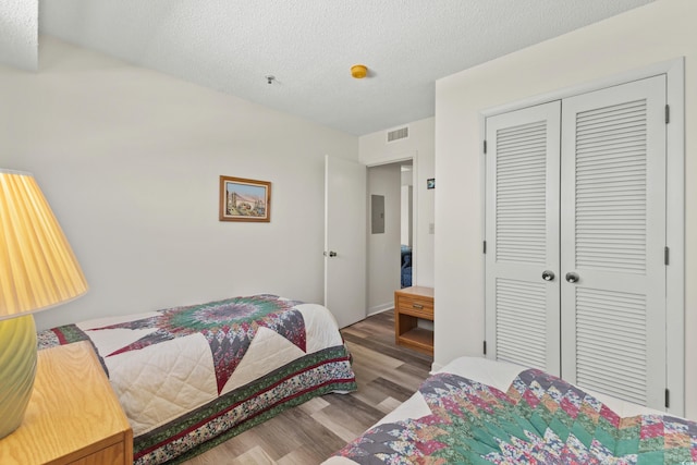 bedroom with a closet, a textured ceiling, and hardwood / wood-style flooring