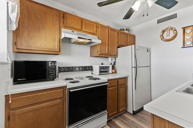 kitchen featuring white appliances, ceiling fan, hardwood / wood-style flooring, and a textured ceiling