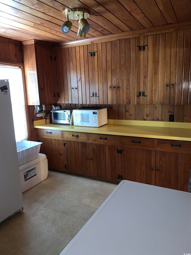 kitchen with wooden ceiling, wood walls, refrigerator, and light tile flooring