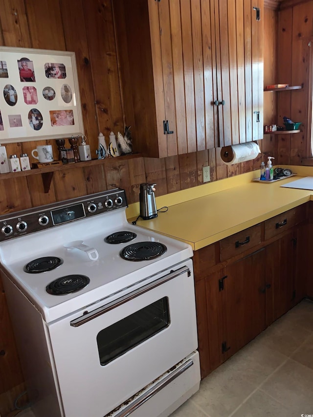 kitchen featuring white range with electric stovetop, light tile floors, and wooden walls