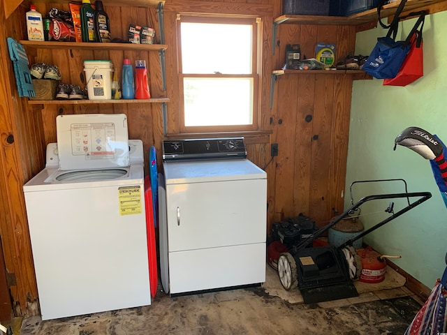 washroom with washing machine and dryer and wood walls