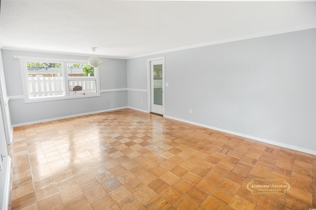 spare room featuring crown molding and a chandelier