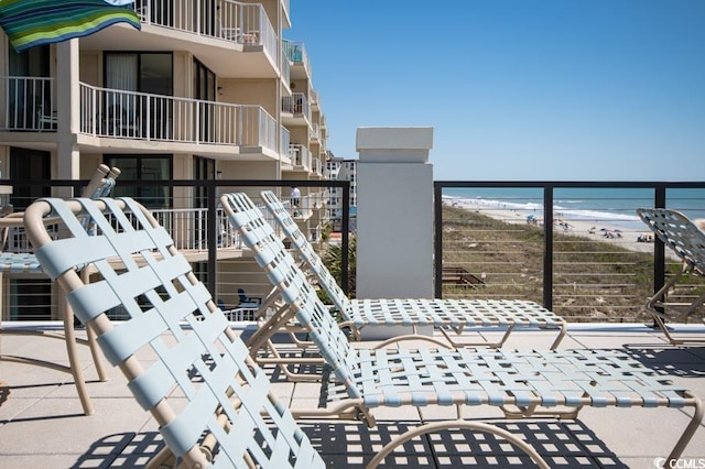 balcony with a water view and a view of the beach