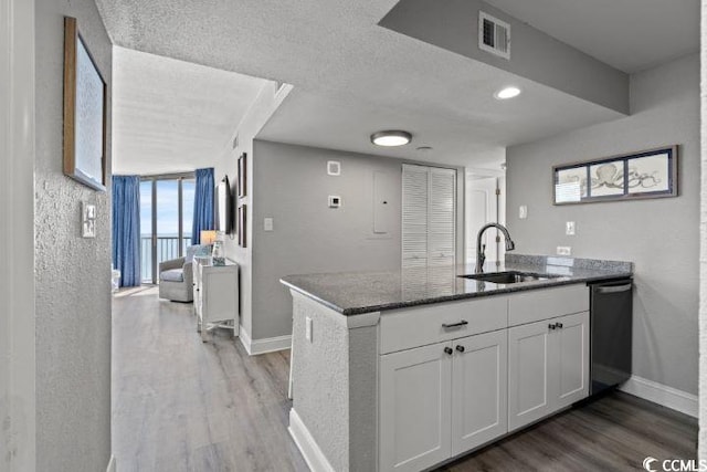 kitchen featuring sink, dishwasher, white cabinetry, light hardwood / wood-style flooring, and kitchen peninsula