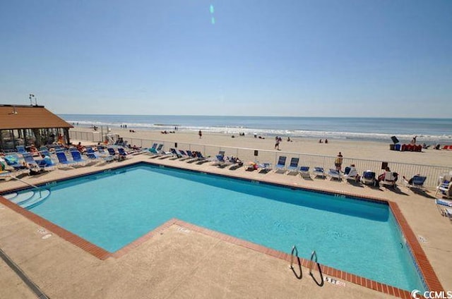 view of pool featuring a water view and a beach view