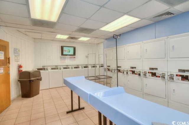 interior space with washer and dryer, stacked washer / dryer, light tile flooring, and a paneled ceiling