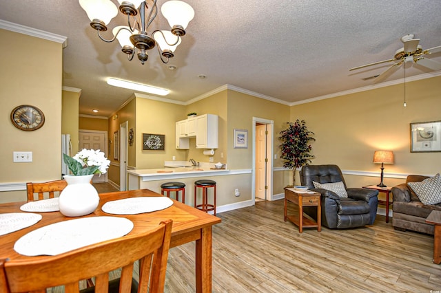 dining area with ornamental molding, light wood-type flooring, and a textured ceiling