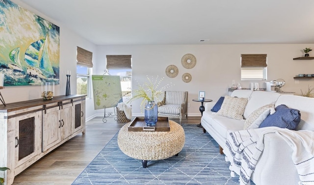 living room with baseboards, visible vents, and wood finished floors