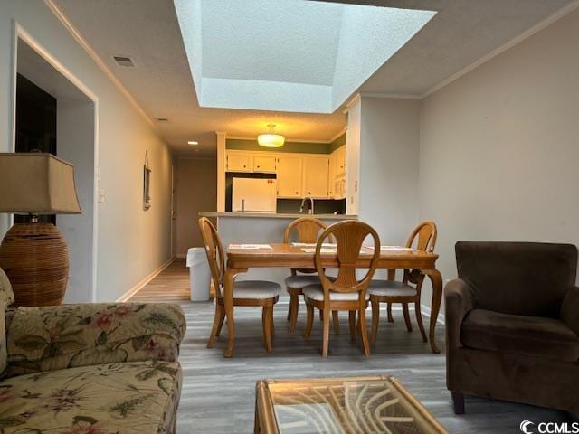 dining area with light hardwood / wood-style flooring, crown molding, and a raised ceiling