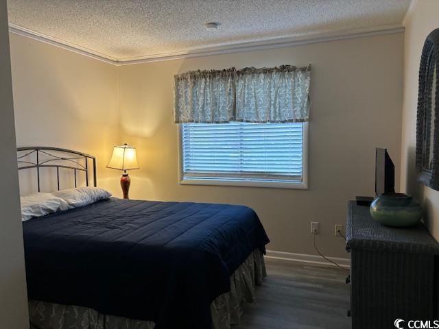 bedroom with a textured ceiling, dark wood-type flooring, and ornamental molding